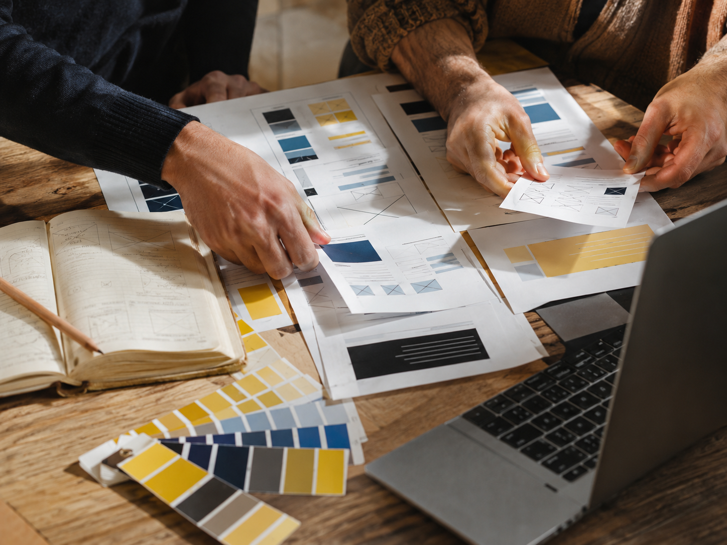 Hands arranging website wireframes and design materials